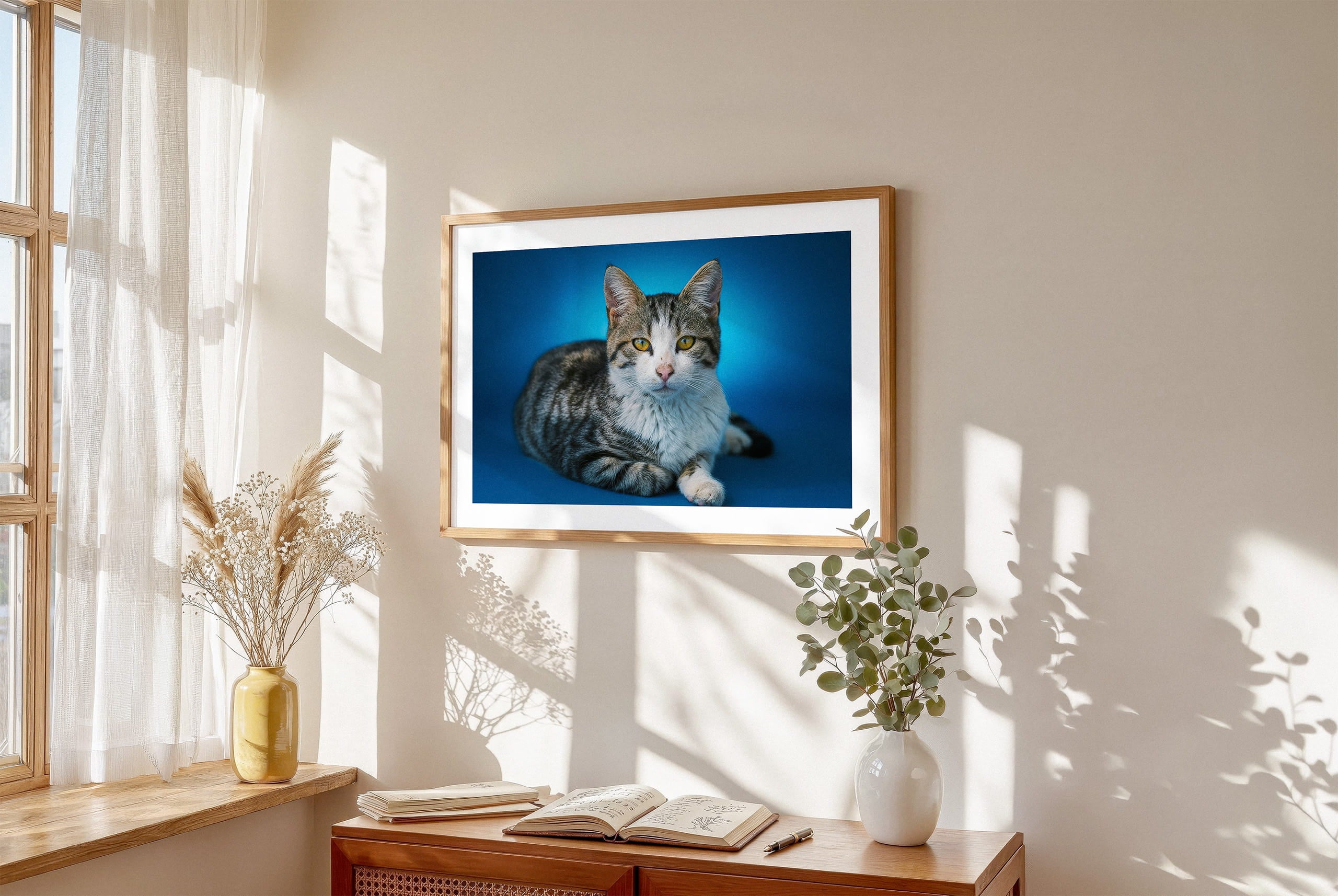 Framed lifestyle mockup of The Statement Gallery — Cerulean by YOUNI.ONE. A bespoke horizontal pet portrait set against a vivid Cerulean studio backdrop, displayed as gallery-style wall art in a warm modern interior.