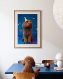 "The Gallery Wall" by YOUNI.ONE. A modern home styling mockup showing a custom bespoke brown poodle portrait in a light wood frame hanging above a dining table. Premium museum-grade pet art curated for pet lovers and stylish living spaces.